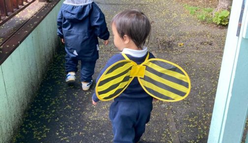 Young boy and girl walking to their nursery classroom. The girl is wearing bee wings